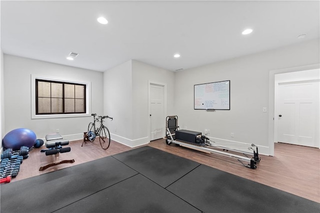 exercise room with visible vents, recessed lighting, baseboards, and wood finished floors