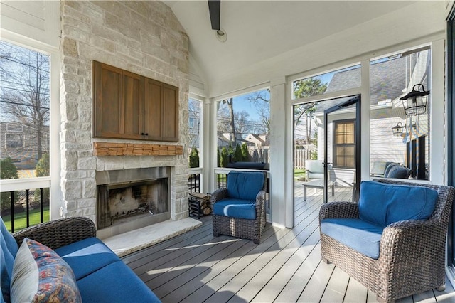 sunroom / solarium featuring a stone fireplace and vaulted ceiling with beams