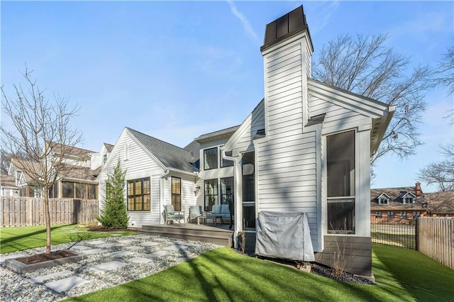 back of house featuring a wooden deck, a lawn, a fenced backyard, and a chimney