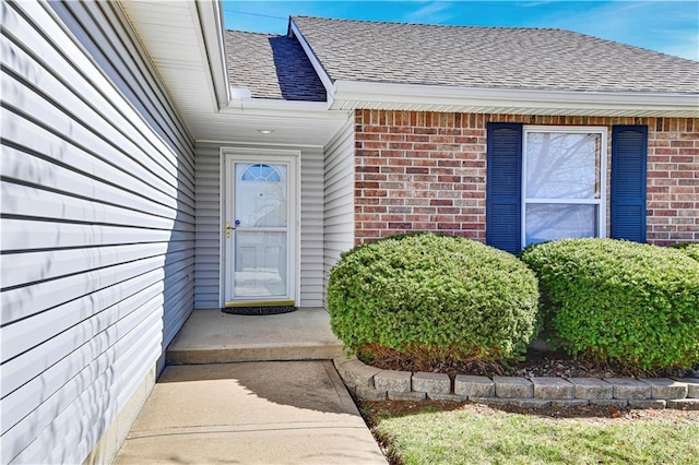 property entrance with brick siding and roof with shingles