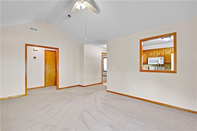 empty room featuring light colored carpet, vaulted ceiling, baseboards, and visible vents