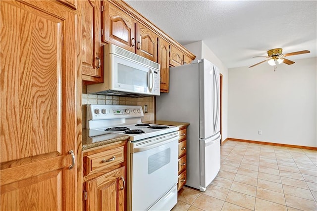 kitchen featuring baseboards, decorative backsplash, light tile patterned flooring, white appliances, and a textured ceiling