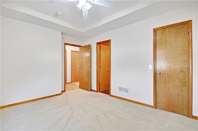 unfurnished bedroom featuring visible vents, baseboards, carpet, and a raised ceiling