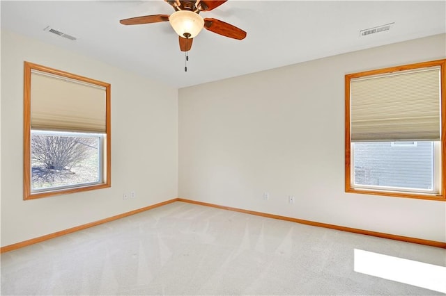 unfurnished room featuring light carpet, visible vents, ceiling fan, and baseboards