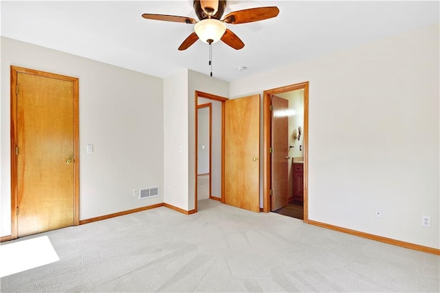 unfurnished bedroom with visible vents, ensuite bathroom, a ceiling fan, baseboards, and light colored carpet