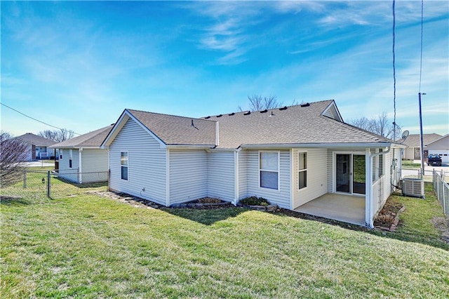 rear view of property featuring central AC unit, fence, roof with shingles, a patio area, and a lawn