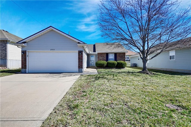 view of front of home with brick siding, an attached garage, concrete driveway, and a front lawn