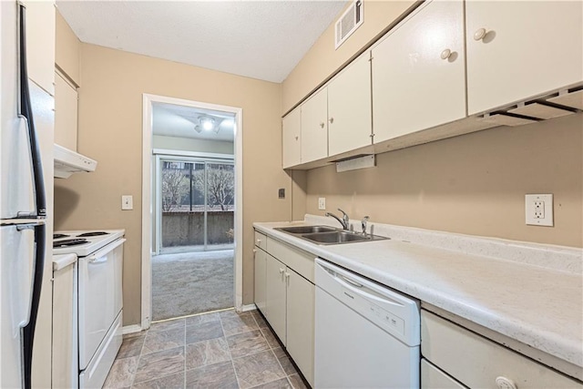 kitchen with white appliances, visible vents, a sink, light countertops, and white cabinets