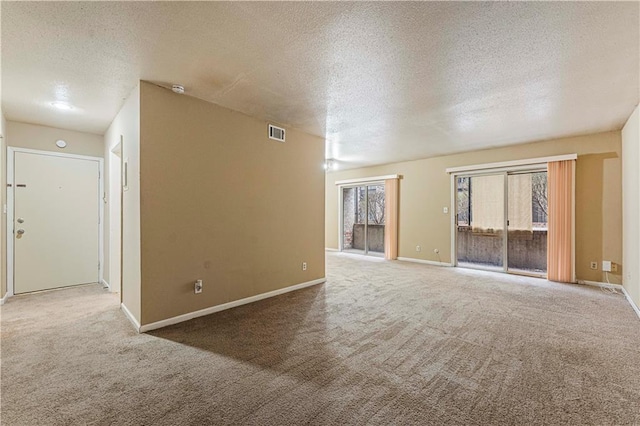 unfurnished room featuring visible vents, carpet floors, a textured ceiling, and baseboards