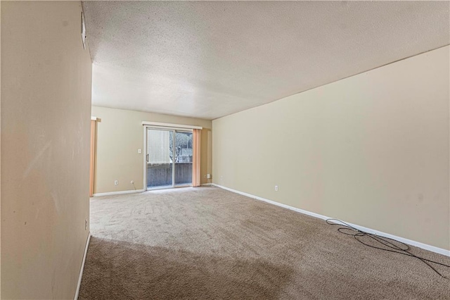 empty room with carpet flooring, a textured ceiling, and baseboards