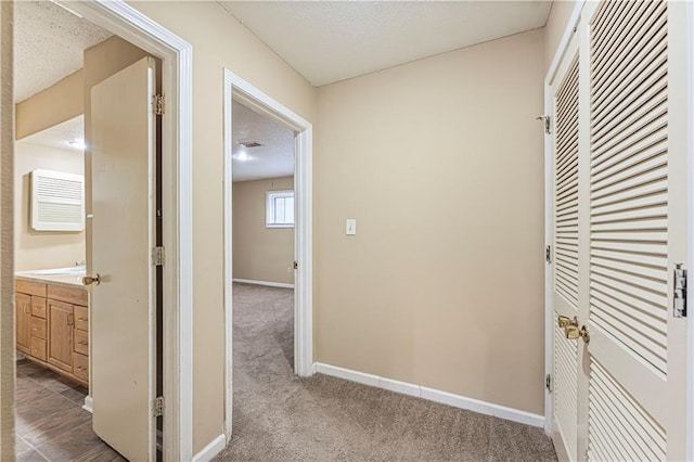 corridor with carpet flooring, baseboards, and a textured ceiling