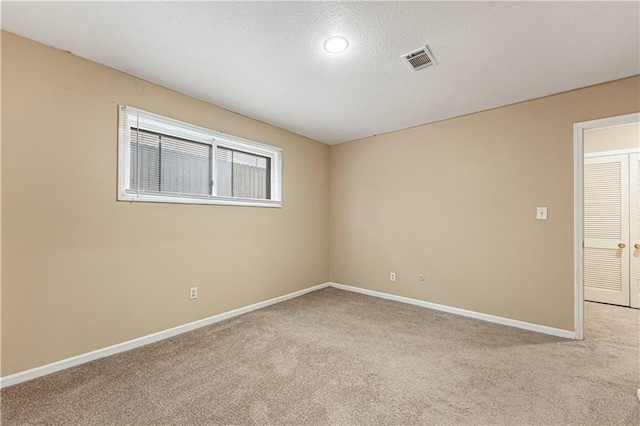 carpeted empty room with baseboards, visible vents, and a textured ceiling