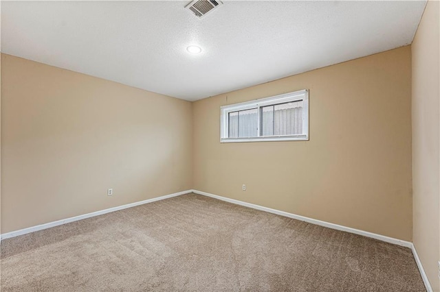 carpeted spare room with visible vents, baseboards, and a textured ceiling