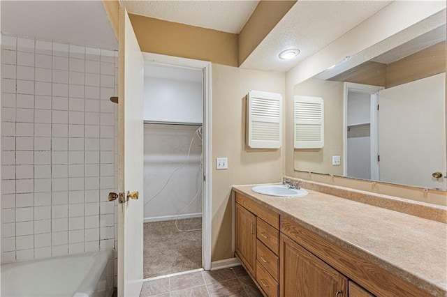 bathroom featuring a walk in closet, baseboards, vanity, a textured ceiling, and  shower combination