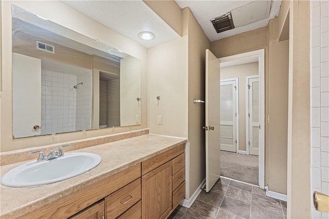 full bathroom with vanity, baseboards, visible vents, and tiled shower