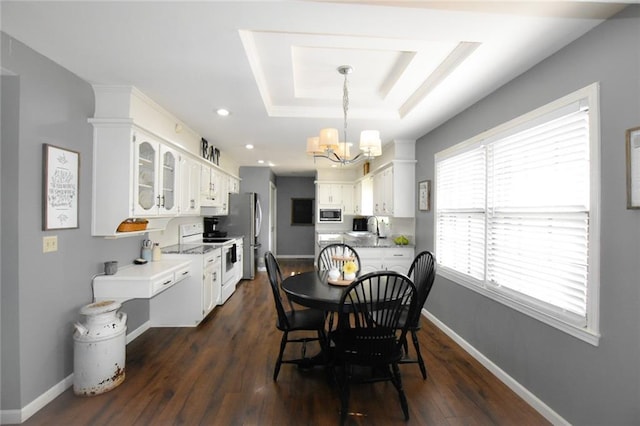 dining area featuring a tray ceiling, dark wood-style floors, baseboards, and a chandelier