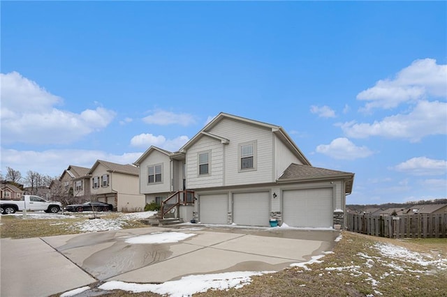 view of front of property with a garage, a residential view, fence, and concrete driveway