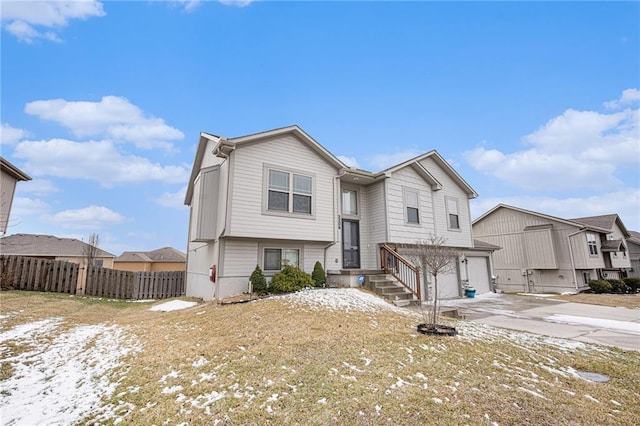 split foyer home featuring a garage, driveway, and fence