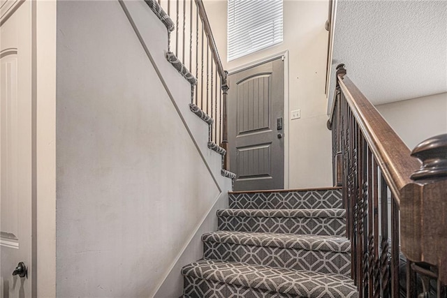 stairs with a textured ceiling and baseboards