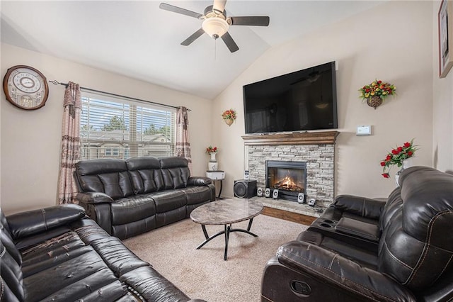 living area featuring vaulted ceiling, ceiling fan, and a stone fireplace