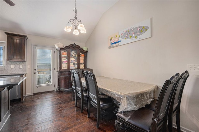 dining area with baseboards, a chandelier, vaulted ceiling, and dark wood-type flooring