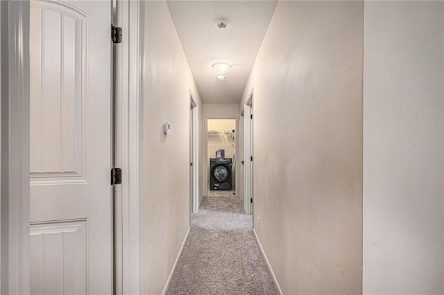 corridor with carpet floors, washer / clothes dryer, a textured ceiling, and baseboards