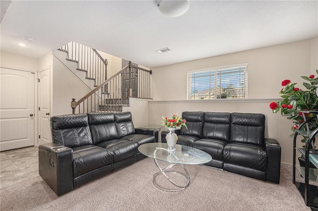 carpeted living area featuring visible vents, stairway, and a textured ceiling