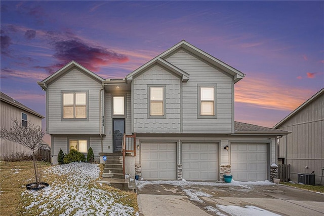 split foyer home with cooling unit, stone siding, and an attached garage