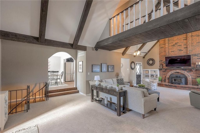 living room featuring arched walkways, ceiling fan, carpet flooring, high vaulted ceiling, and beam ceiling