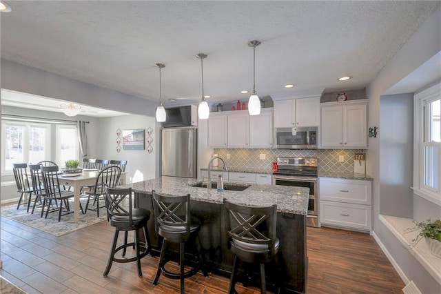 kitchen featuring stainless steel appliances, dark wood finished floors, a sink, and backsplash