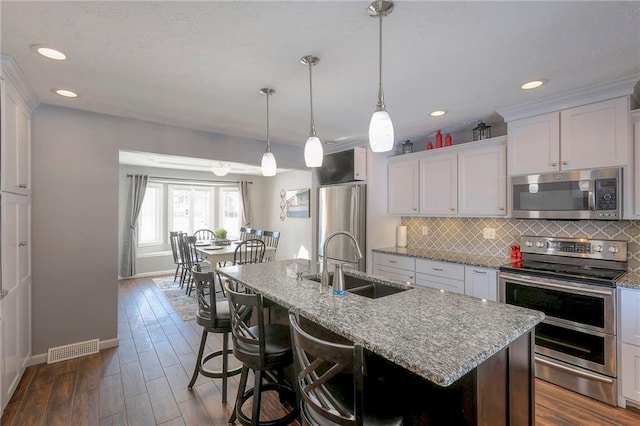 kitchen featuring stainless steel appliances, dark wood-type flooring, a sink, and decorative backsplash