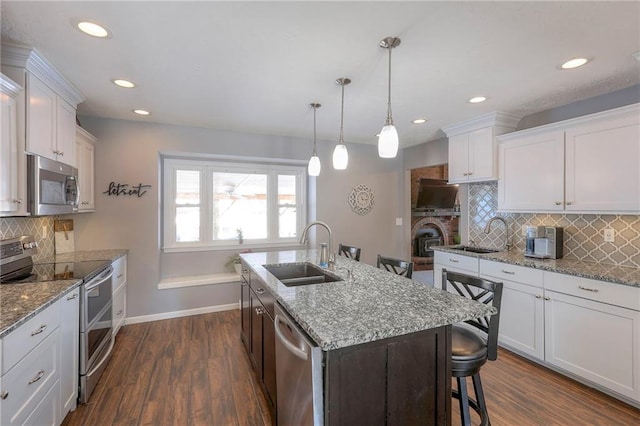 kitchen featuring appliances with stainless steel finishes, dark wood finished floors, a sink, and a kitchen breakfast bar