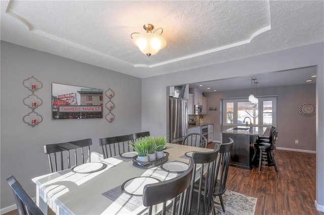 dining space featuring a textured ceiling, baseboards, and dark wood-type flooring