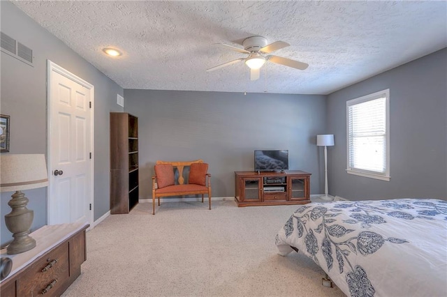 bedroom with a textured ceiling, light carpet, visible vents, baseboards, and a ceiling fan