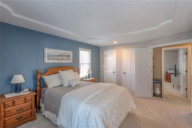 bedroom with light carpet, a textured ceiling, and two closets