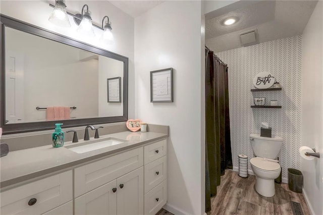 full bath with toilet, baseboards, wood finished floors, and vanity