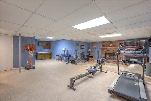 workout room featuring a drop ceiling, a fireplace, and visible vents