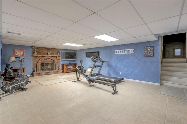 workout area with visible vents, a fireplace, a paneled ceiling, and baseboards