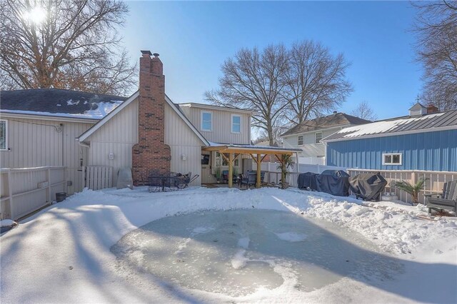 snow covered house featuring fence and a chimney