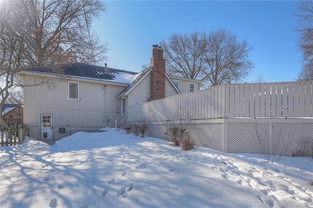 snow covered house featuring a chimney