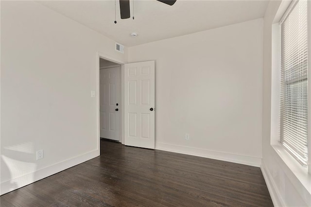 empty room with a ceiling fan, baseboards, visible vents, and dark wood-style flooring