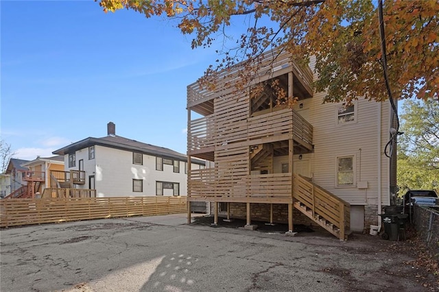 rear view of property with fence, a balcony, and stairs