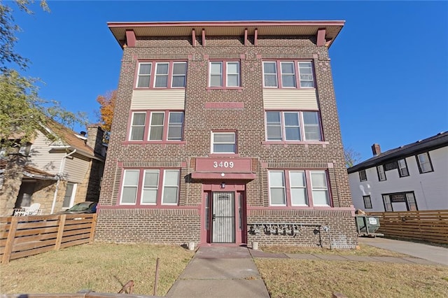 view of front of property featuring a front yard, brick siding, and fence