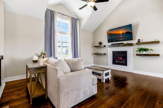 living area featuring lofted ceiling, hardwood / wood-style flooring, baseboards, ceiling fan, and a tile fireplace