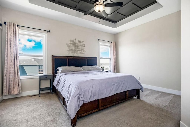 carpeted bedroom with ceiling fan, baseboards, and a tray ceiling