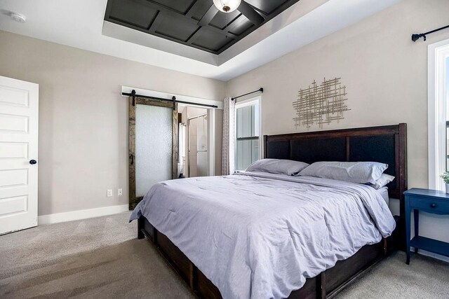 carpeted bedroom featuring a barn door and baseboards