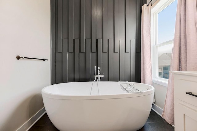 full bathroom with tile patterned floors, a freestanding tub, and baseboards