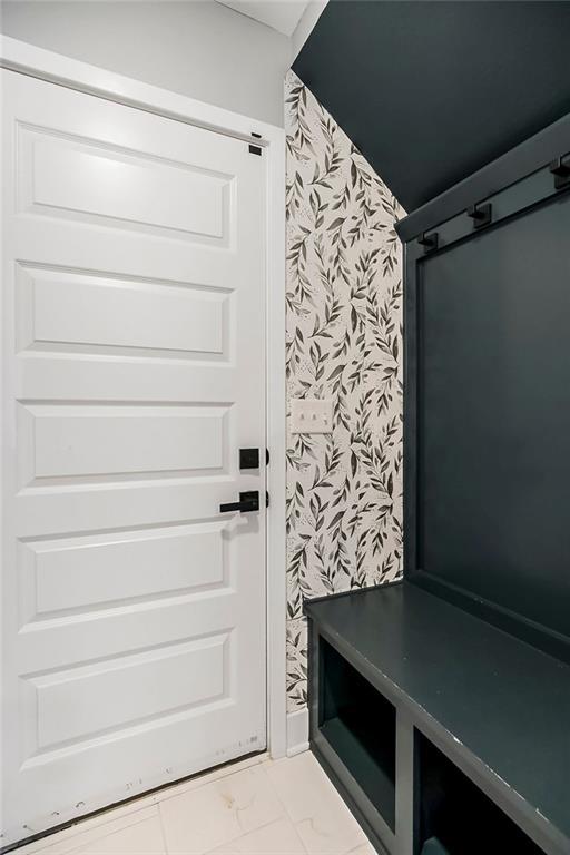 mudroom featuring marble finish floor and wallpapered walls