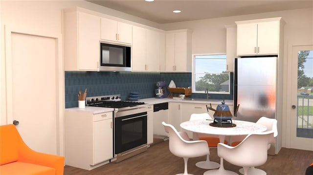 kitchen with light countertops, decorative backsplash, appliances with stainless steel finishes, wood finished floors, and a sink