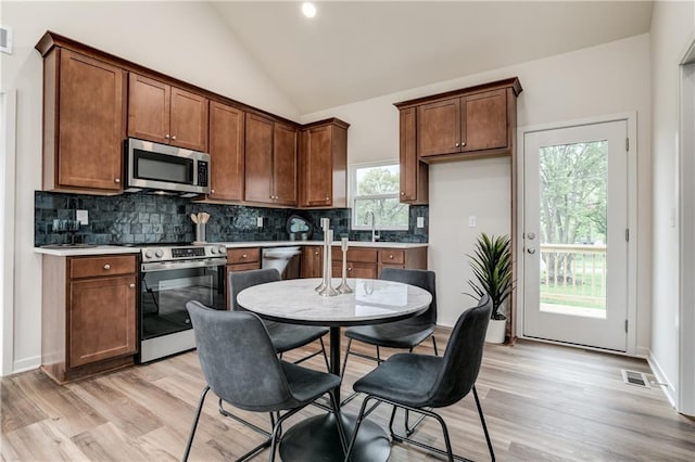 4413 E 135th St, Grandview, MO 64030 - kitchen featuring appliances with stainless steel finishes, tasteful backsplash, vaulted ceiling, light wood-type flooring, and light countertops